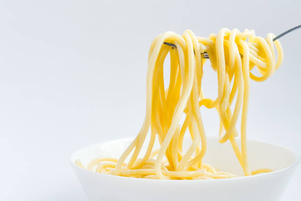 istock Spaghetti without sauce with a fork in a white plate, isolated on a white background. Flour products, long pasta hanging on a fork, gluten and balanced nutrition. 2166935240