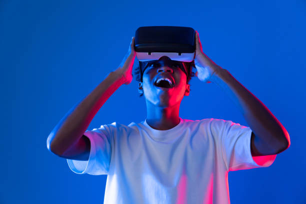 istock Surprised African looking VR holding object hologram neon wall. Contrivance. 2166945197