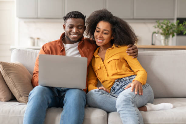 istock Happy Black Couple Embracing Browsing Internet On Laptop At Home 2166948534