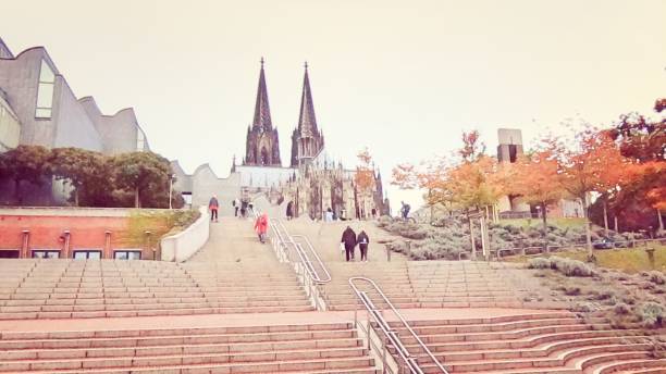 Tourists and commuters outside Germany's most visited landmark Cathedral Church of Saint Peter, Cologne , North Rhine-Westphalia - Germany (Kölner Dom, officially Hohe Domkirche Sankt Petrus). It is the seat of the Archbishop of Cologne and of the administration of the Archdiocese of Cologne
