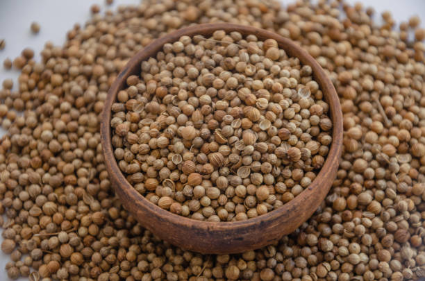 istock Coriander seeds in a wooden plate on a white background 2166961827