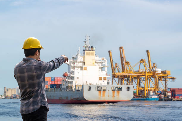 istock Dock worker guiding cargo ship at port 2166963757