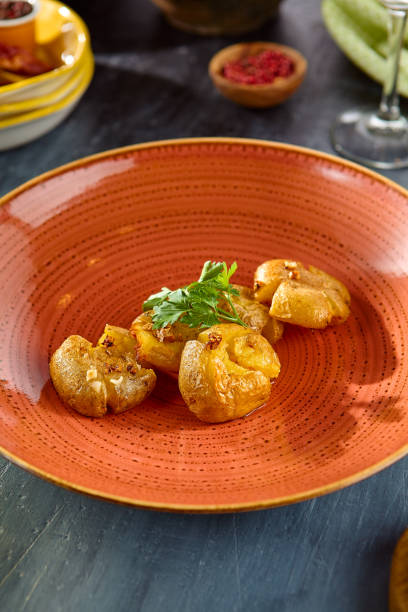istock Smashed and Baked Baby Potatoes Garnished with Fresh Herbs on Rustic Plate 2166966369