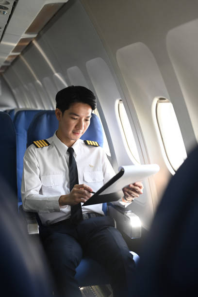 istock Smiling asian pilot with clipboard checking flight plan or preparing flight procedures in the cabin 2166966928