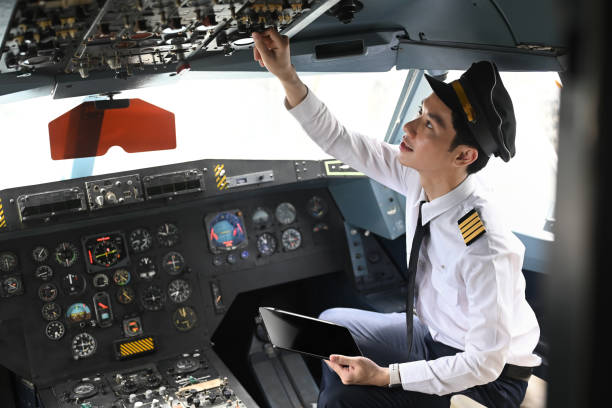 istock Pilot with digital tablet sitting in cockpit and adjusting controls on the overhead panel 2166966958