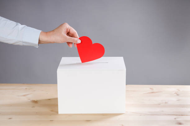 istock Female hand putting red heart into donation box 2166971510