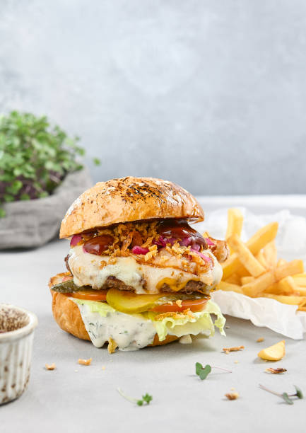 istock Juicy Burger with Patty, Two Sauces, and Fries on a Rustic Table 2166972178