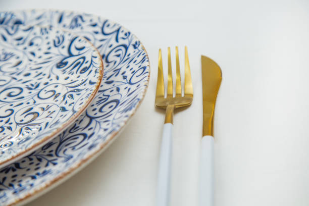 istock On the side, two serving plates with blue patterns on a white background stand one on one, part of the plates is visible, gold-white appliances are located on the side, a close-up side view on a white background. 2166978161