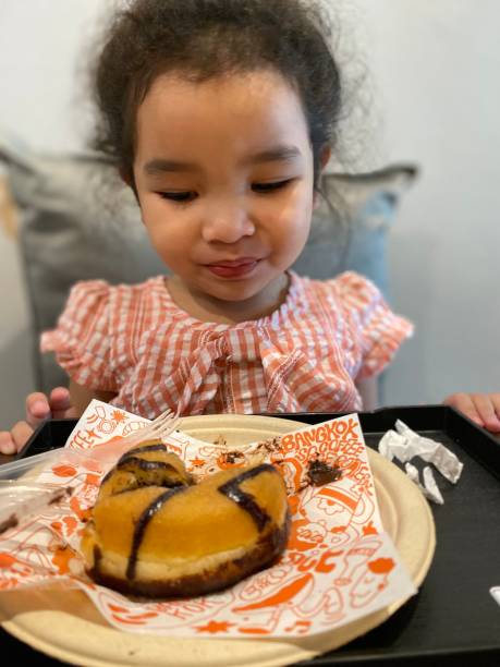 istock Little girl eating a donut in the kitchen. Selective focus. 2166980601