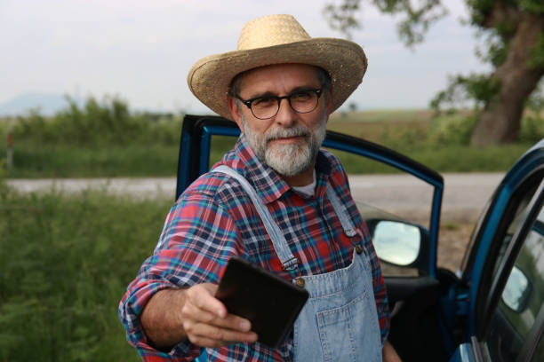 Portrait of a Old, Frustrated, wrinkled and expressive old, Lonely farmer outdoor looking at camera, while standing outside an old rustic wooden barn or house.