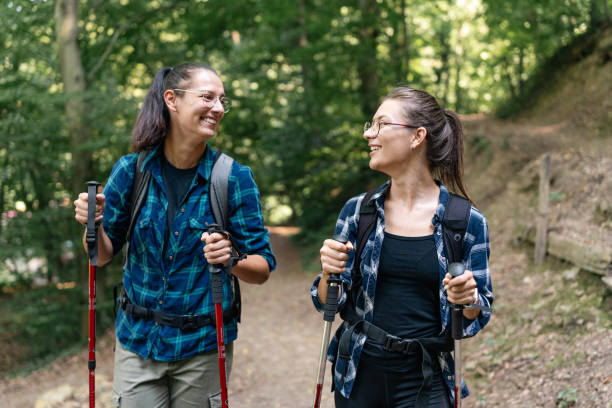 istock Two hikers smiling on a forest trail holding poles. 2166988676