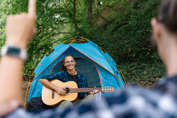 istock Person playing guitar at campsite with forest background. 2166989141