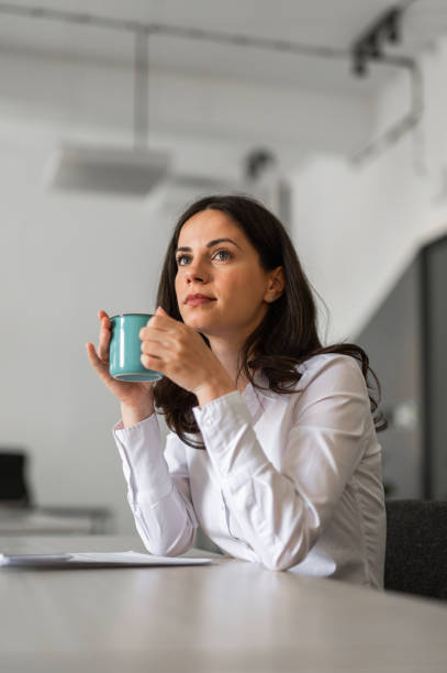 istock Young office employee having a cup of coffee while sitting at her desk 2166991075