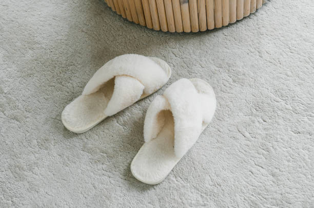 istock Cozy White Slippers Next to a Wicker Basket on a Plush Carpet 2166991301