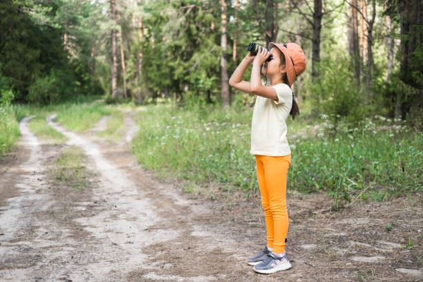 Cute little girl exploring nature looking through binoculars