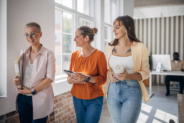 istock Three colleagues walking and smiling in office hallway. 2166998879