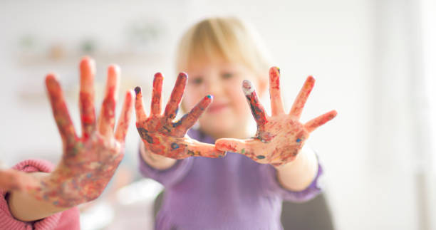 istock Two sisters making finger paintings and showing their hands 2166999456