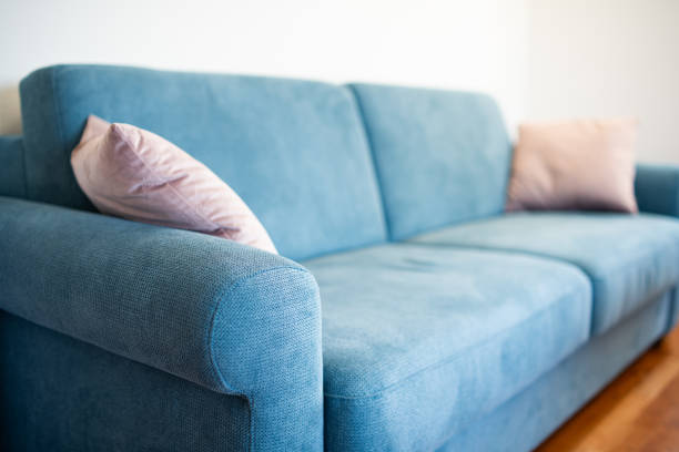 istock Light blue fabric sofa with cushions inside apartment room. Close up, side view, shallow depth of field, no people 2166999738