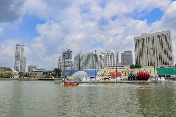 Singapore City, Singapore - July 19, 2023: The skyline of Singapore showcases a mix of modern buildings along the waterfront, with boats enjoying a calm day beneath a partly cloudy sky.