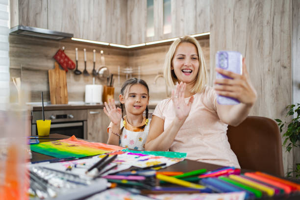 istock Mother and daughter video chatting while creating art in a cozy kitchen setting 2167001035