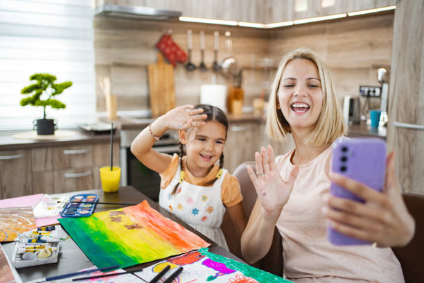 istock Mother and daughter enjoying art time while video chatting in a cozy kitchen 2167001091