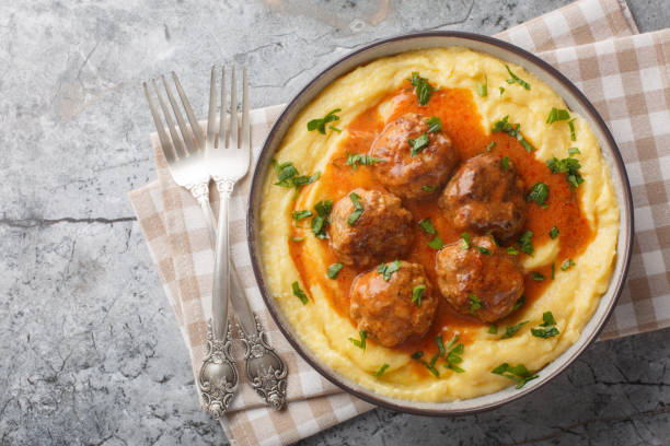 Baked corn porridge with meatballs and spicy gravy close-up in a bowl. Horizontal top view stock photo