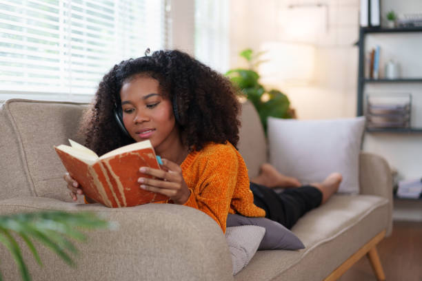istock African American Woman Relaxing on Couch While Reading Book at Home. 2167005932