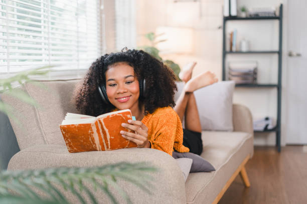 istock African American Woman Relaxing on Couch While Reading Book at Home. 2167005943