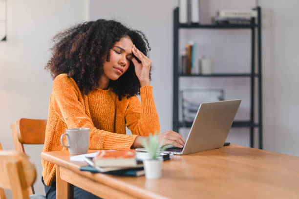 istock African American woman holding her forehead in frustration while working on a laptop, showcasing stress and exhaustion. 2167006056