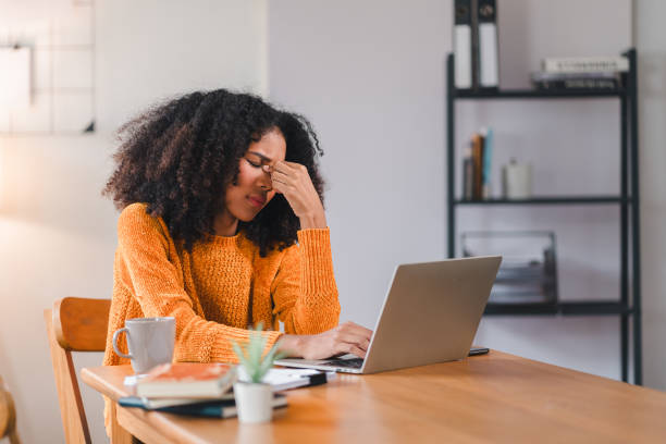 istock African American woman holding her forehead in frustration while working on a laptop, showcasing stress and exhaustion. 2167006063