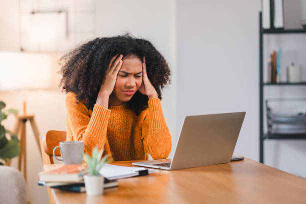 istock African American woman holding her forehead in frustration while working on a laptop, showcasing stress and exhaustion. 2167006065