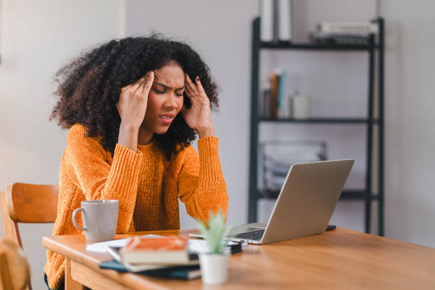 istock African American woman holding her forehead in frustration while working on a laptop, showcasing stress and exhaustion. 2167006071