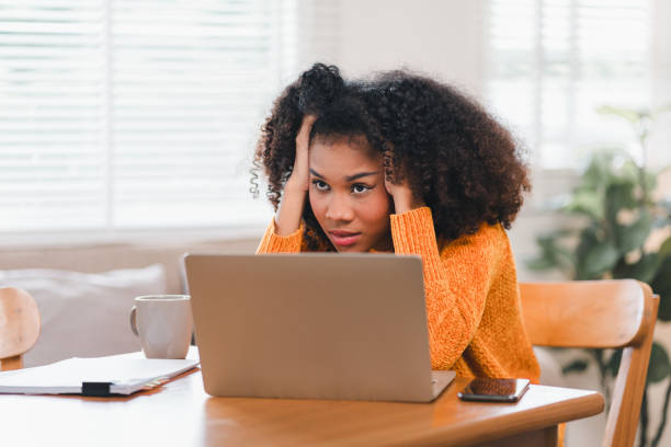 istock African American woman holding her forehead in frustration while working on a laptop, showcasing stress and exhaustion. 2167006083