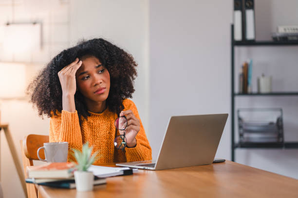 istock African American woman holding her forehead in frustration while working on a laptop, showcasing stress and exhaustion. 2167006092