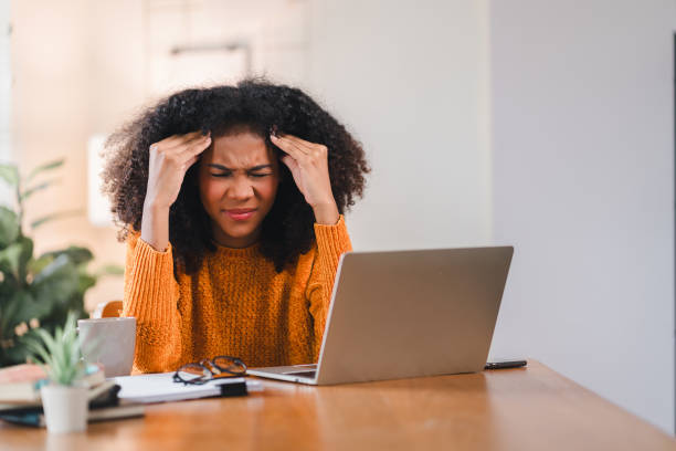 istock African American woman holding her forehead in frustration while working on a laptop, showcasing stress and exhaustion. 2167006987