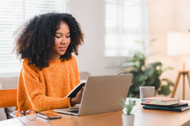 istock Smiling African American woman reading a notebook while working at home. 2167007071