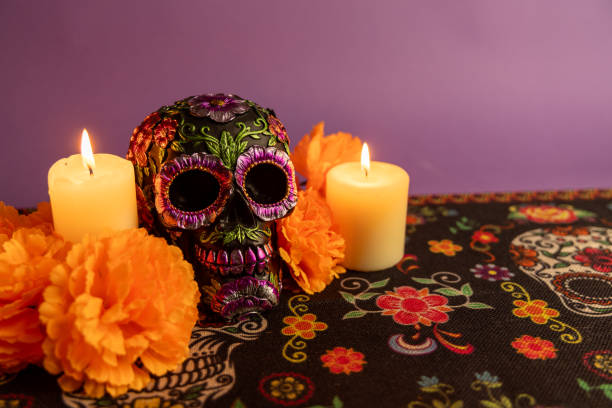 istock A skull adorned with metallic flowers, flanked by two flickering candles. Surrounded by vibrant orange flowers 2167009568
