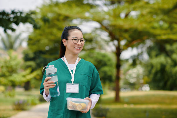 istock Smiling Nurse Holding Water Bottle and Lunch Box Outside 2167009641