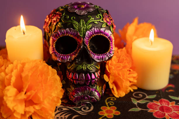 istock A beautifully adorned skull with metallic flowers and two lit candles on either side. Surrounded by vibrant orange flowers 2167009893