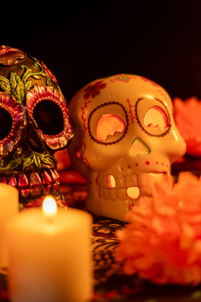 istock In this vertical shot, two skulls are prominently displayed: one with metallic floral decorations and one with a candle inside. Both are surrounded by vibrant marigold flowers and lit candles 2167009986