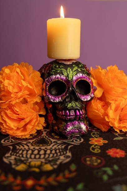 istock A skull adorned with metallic flowers and a lit candle on its head, surrounded by orange flowers in a vertical frame 2167010073