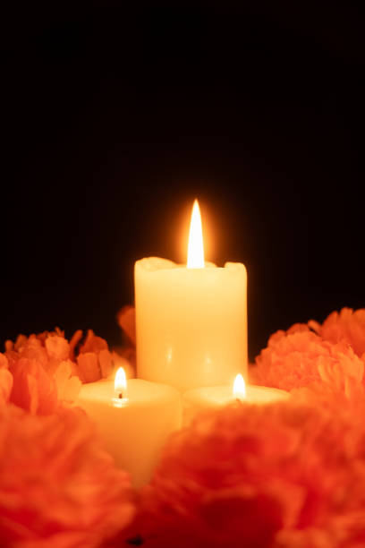 istock A vertical view showing three glowing candles surrounded by bright orange marigold flowers 2167010334