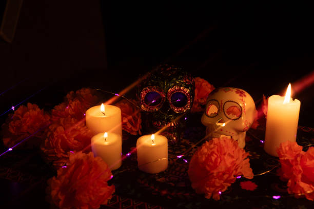 istock A captivating scene of two skulls: one adorned with metallic flowers and another with a lit candle inside 2167010367