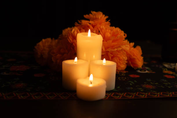 istock Three candles emit a warm light, surrounded by marigold blooms. 2167010387
