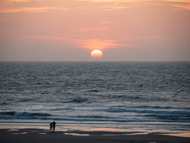 Beautiful sunset over the North Sea in Middelkerke, West Flanders, Belgium. Two silhouettes op people near the water.