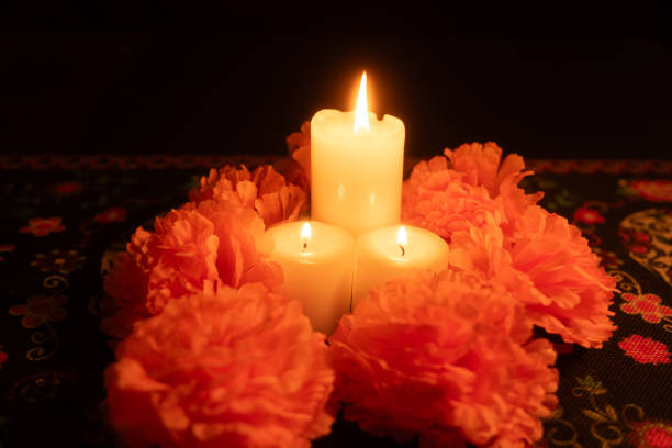 istock Three glowing candles surrounded by bright orange marigolds on a black background 2167010731