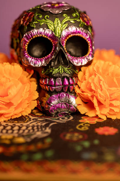istock Close-up vertical view of a skull adorned with metallic floral decorations, surrounded by bright orange marigolds 2167010794