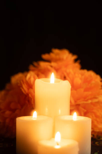 istock Vertical image showing three candles burning brightly, surrounded by marigold flowers 2167011389