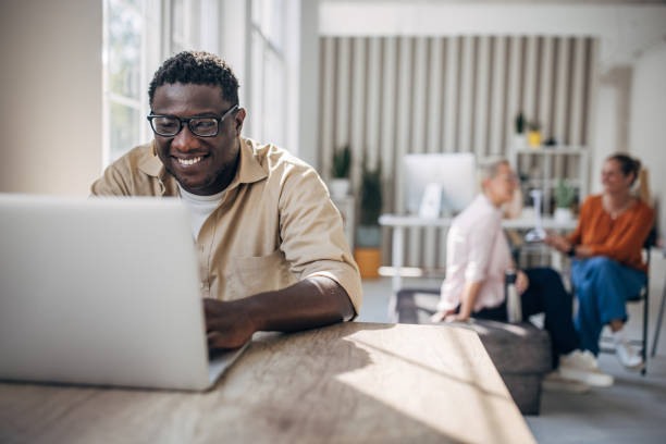 istock Man focused on laptop with colleagues in background 2167018176