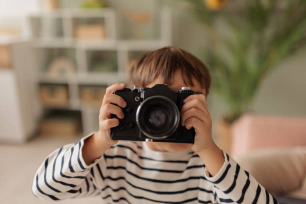 istock Little boy playing with a film camera at home 2167021581